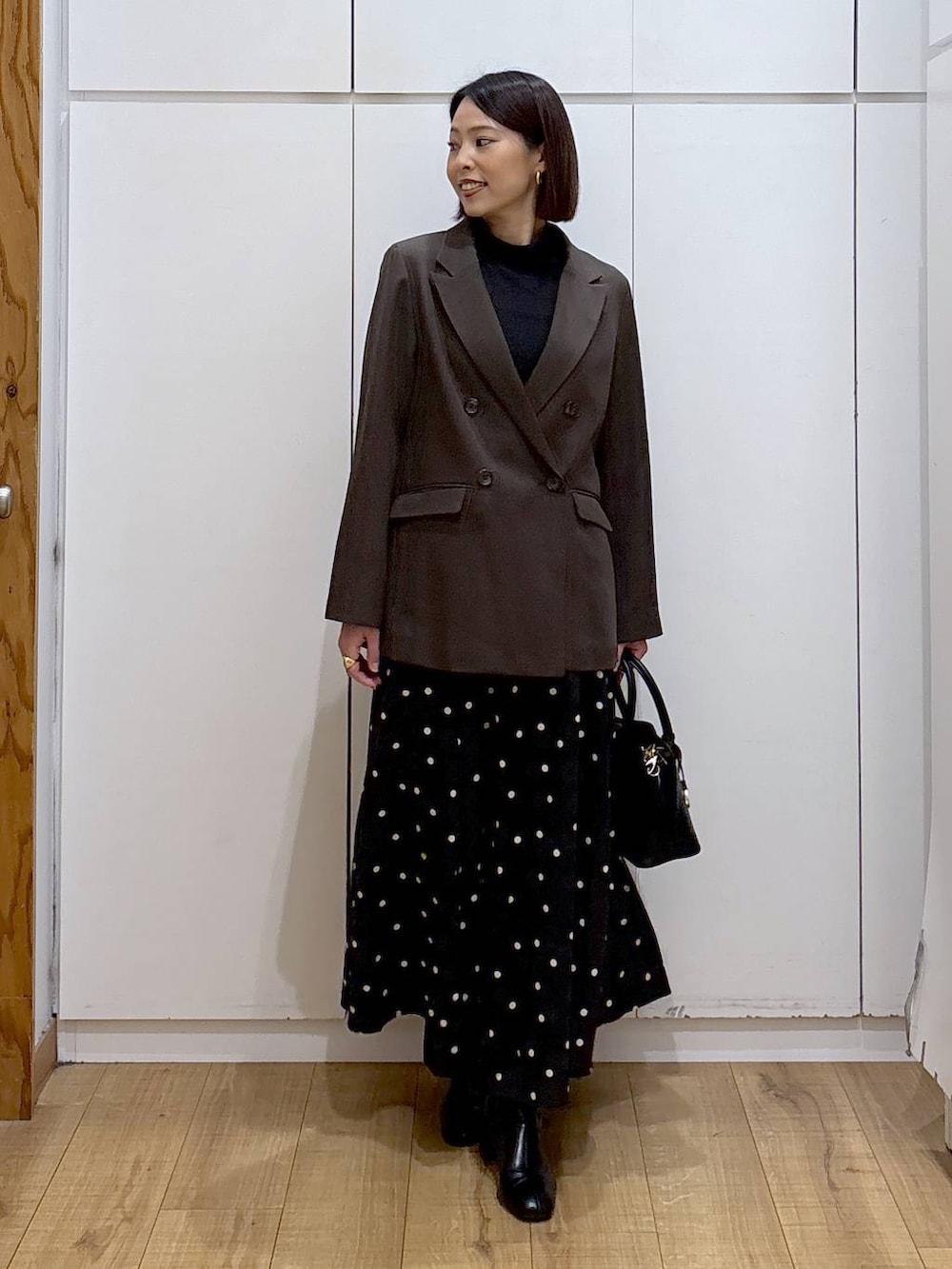 ブラック系のショルダーバッグ、ブラック系のTシャツ/カットソー、ブラック系のブーツを着用したレディースの冬コーディネートの2枚目の写真