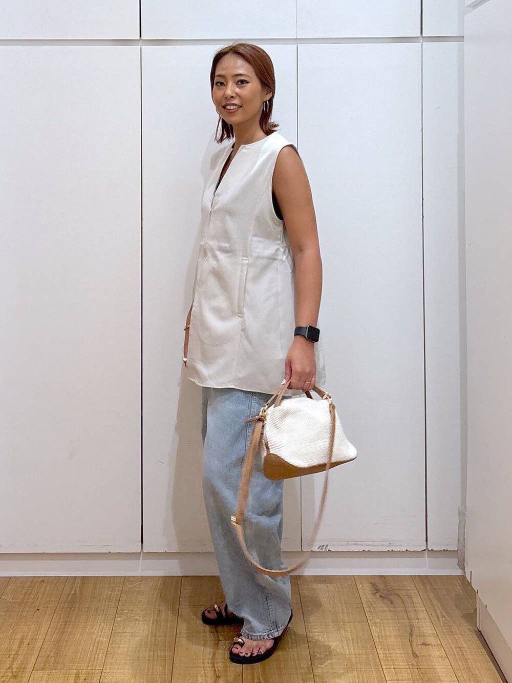 ブルー系のデニムパンツ、ホワイト系のショルダーバッグ、ブラック系のキャミソールを着用したレディースの夏コーディネートの5枚目の写真