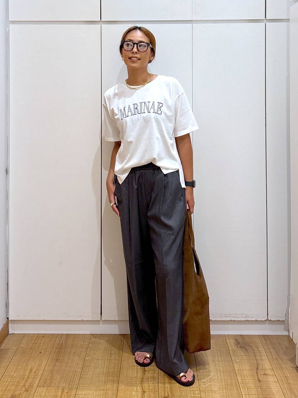 ホワイト系のTシャツ/カットソー、ブラウン系のサンダル、グレー系のその他パンツを着用したレディースの秋コーディネートの3枚目の写真