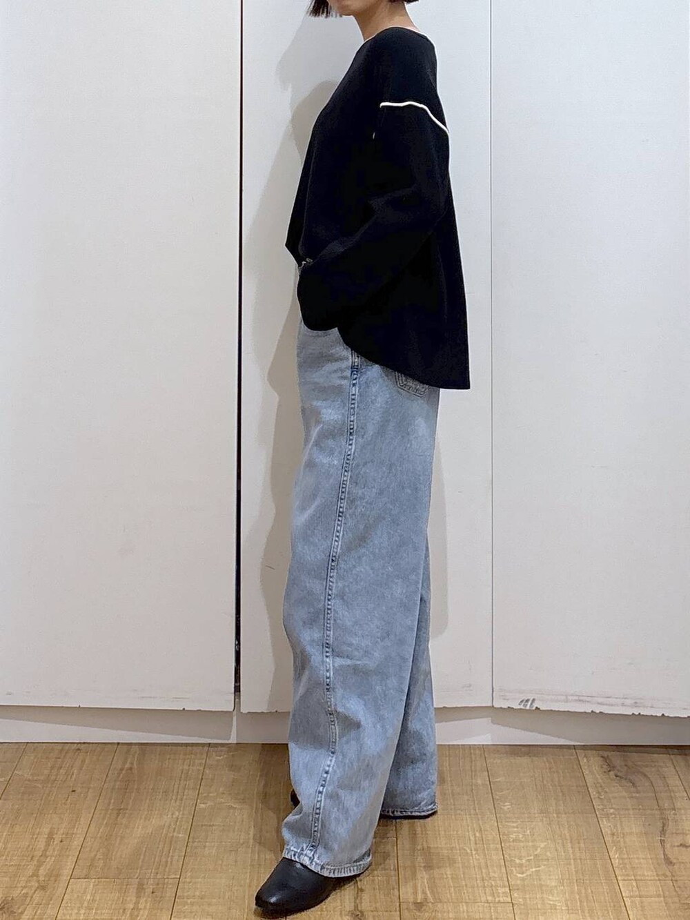 ブルー系のデニムパンツ、ブラック系のワンピース、ブラック系のブーツを着用したレディースの冬コーディネートの2枚目の写真