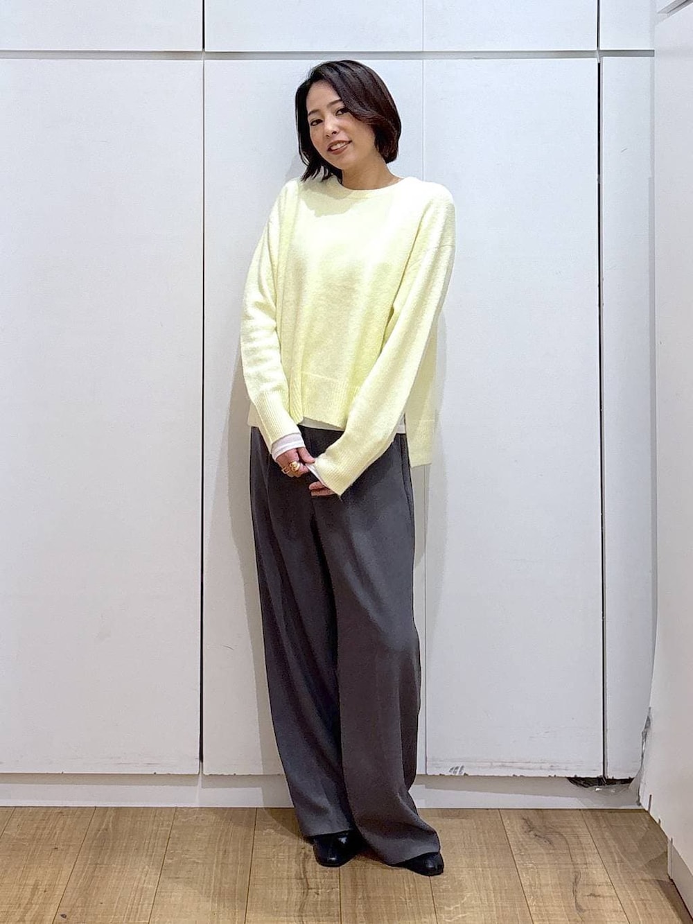 イエロー系のニット/セーター、ブラック系のブーツ、ゴールド系のピアス（両耳用）を着用したレディースの冬コーディネートの6枚目の写真