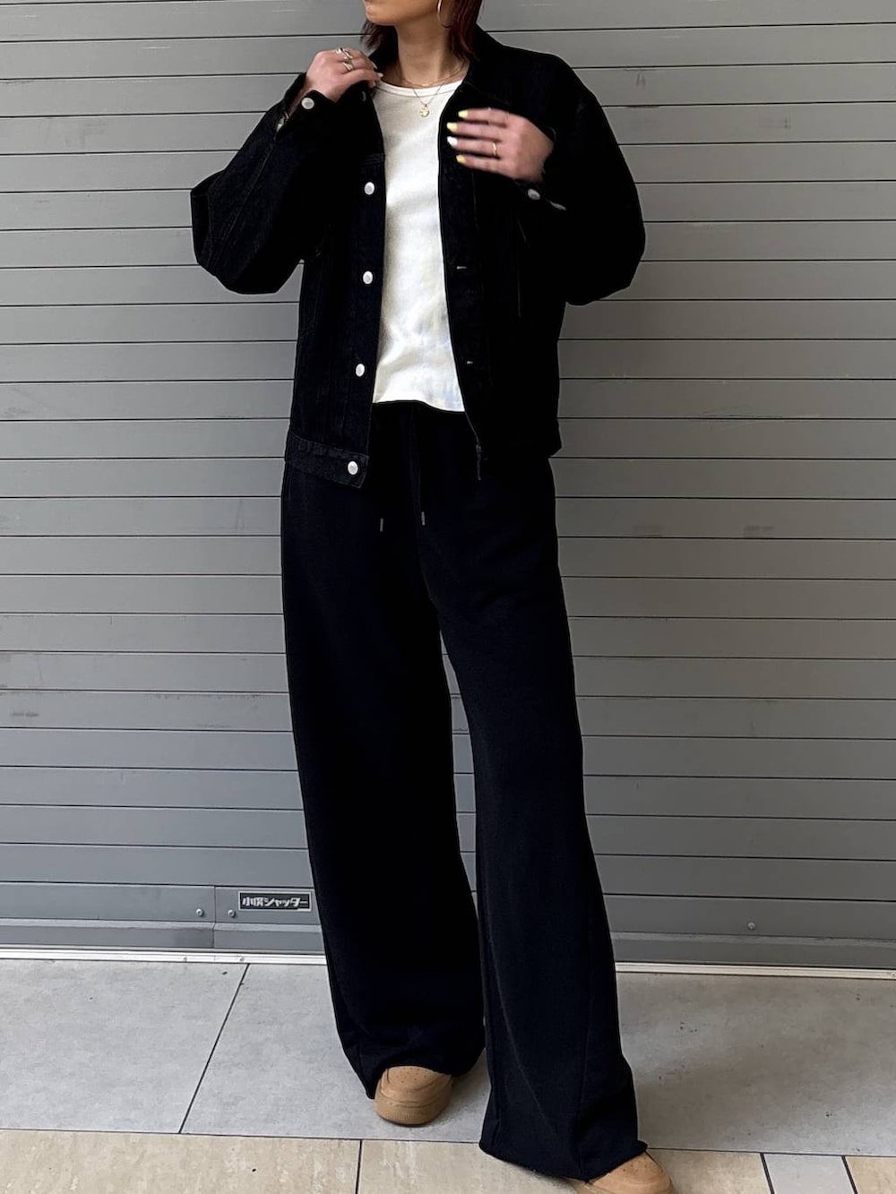 ブラック系のデニムジャケット、ブラック系のスウェットパンツ、ゴールド系のネックレスを着用したレディースの春コーディネートの5枚目の写真