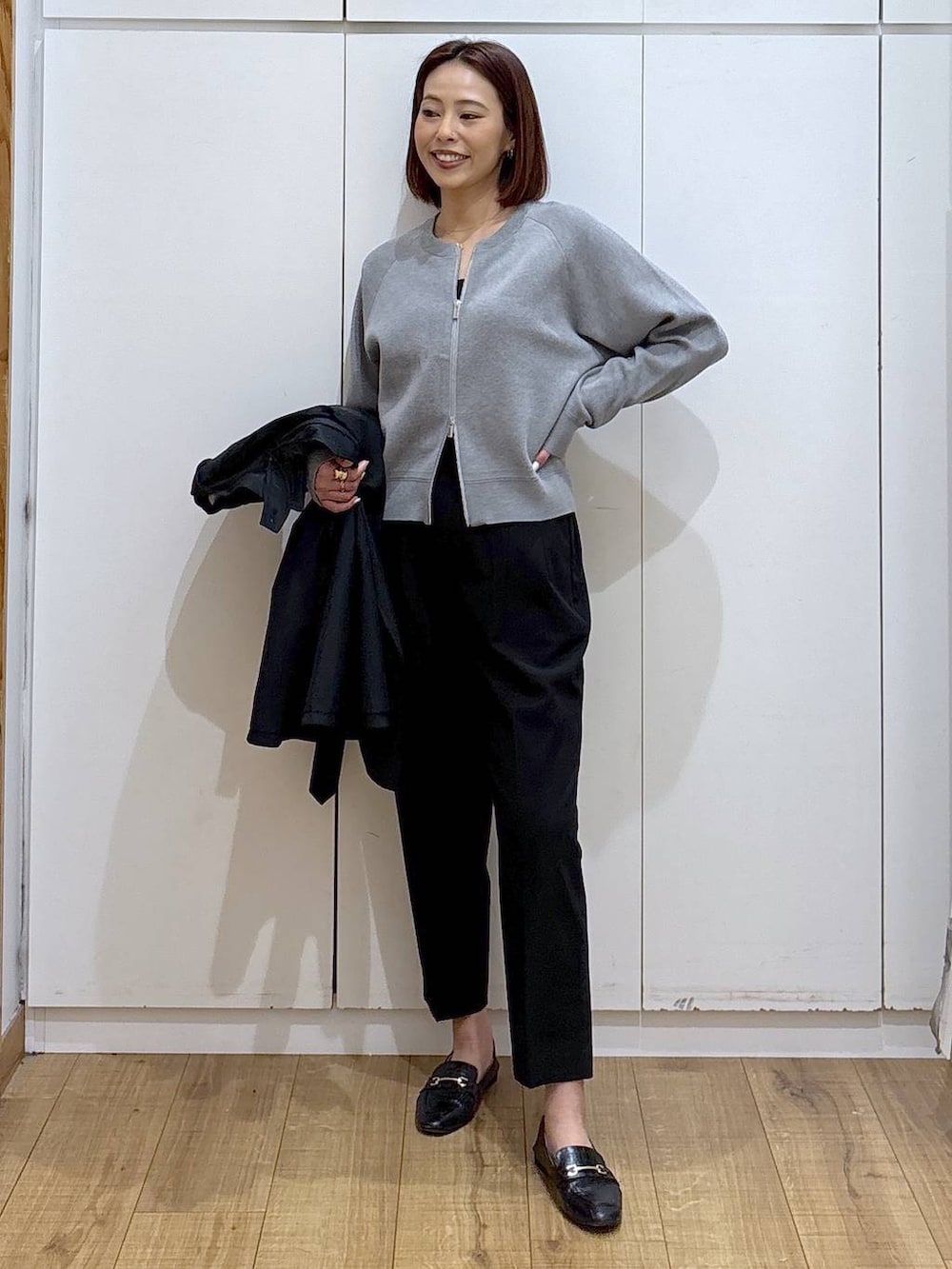 ブラック系のローファー、ブラック系のスラックス、ブルー系のトレンチコートを着用したレディースの春コーディネートの3枚目の写真