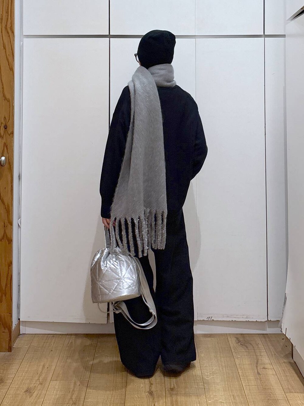 ブラック系のニット/セーター、シルバー系のハンドバッグ、ホワイト系のTシャツ/カットソーを着用したレディースの冬コーディネートの2枚目の写真