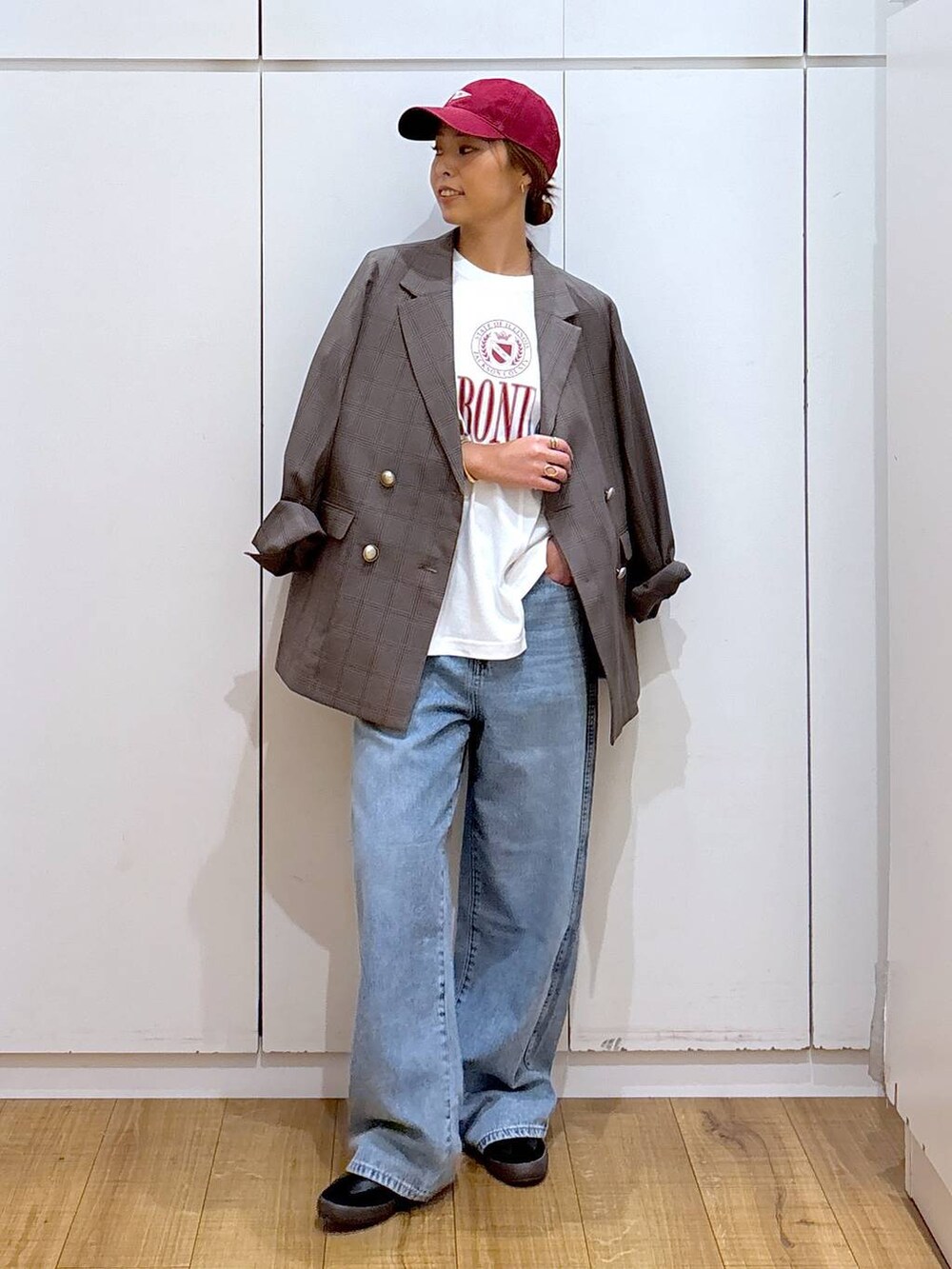 ブラック系のスニーカー、ブラウン系のテーラードジャケット、ブルー系のデニムパンツを着用したレディースの秋コーディネートの2枚目の写真