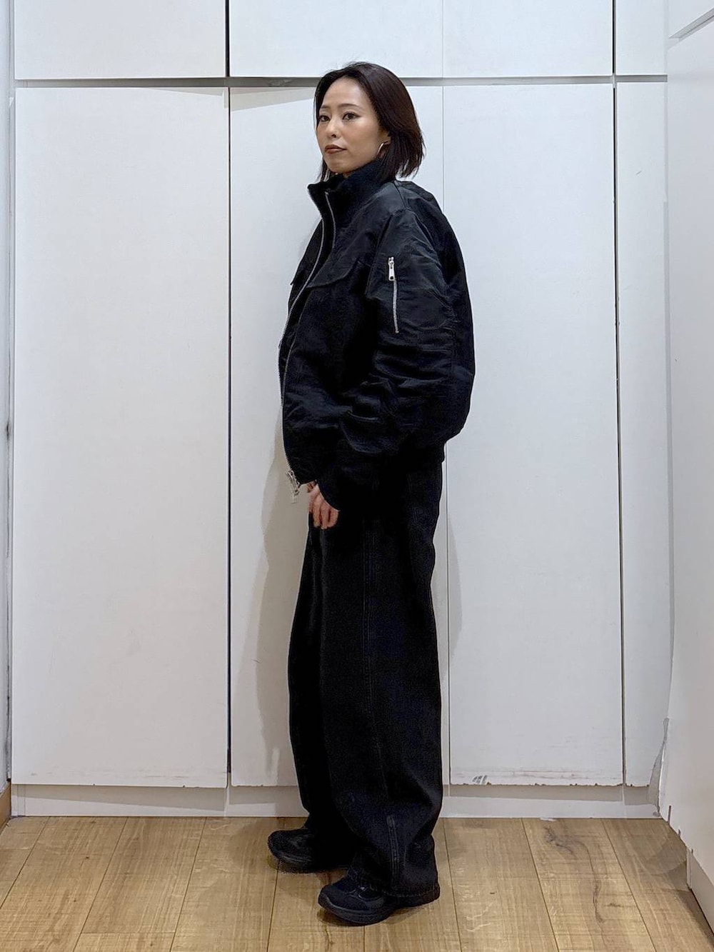 ブラック系のデニムパンツ、ブラック系のスニーカー、ホワイト系のTシャツ/カットソーを着用したレディースの秋コーディネートの3枚目の写真