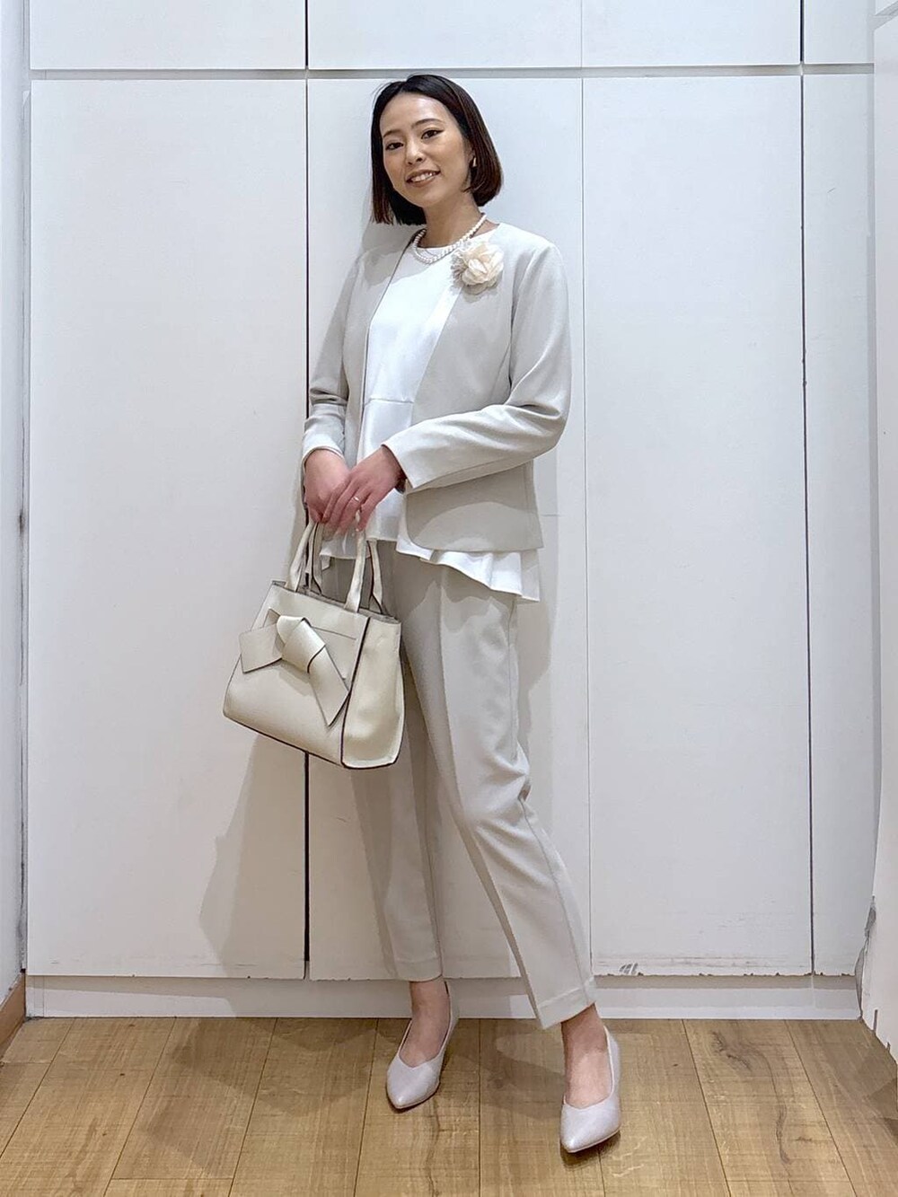 ホワイト系のパンプス、ベージュ系のセットアップ、ベージュ系のハンドバッグを着用したレディースの冬コーディネートの4枚目の写真