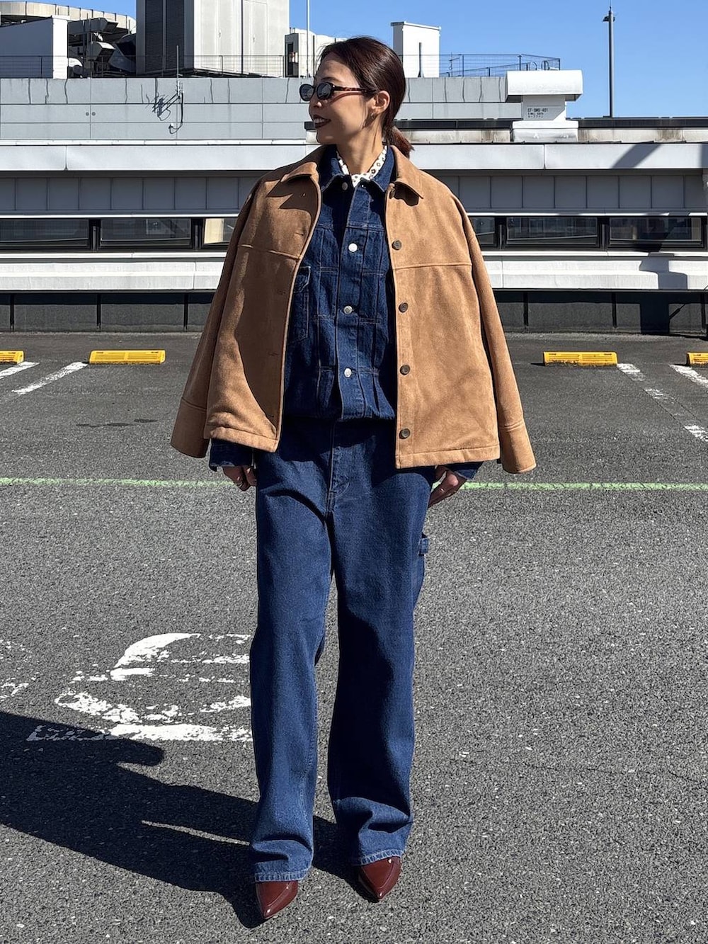 ブルー系のデニムジャケット、ブラウン系のテーラードジャケット、ブルー系のデニムパンツを着用したレディースの冬コーディネートの4枚目の写真