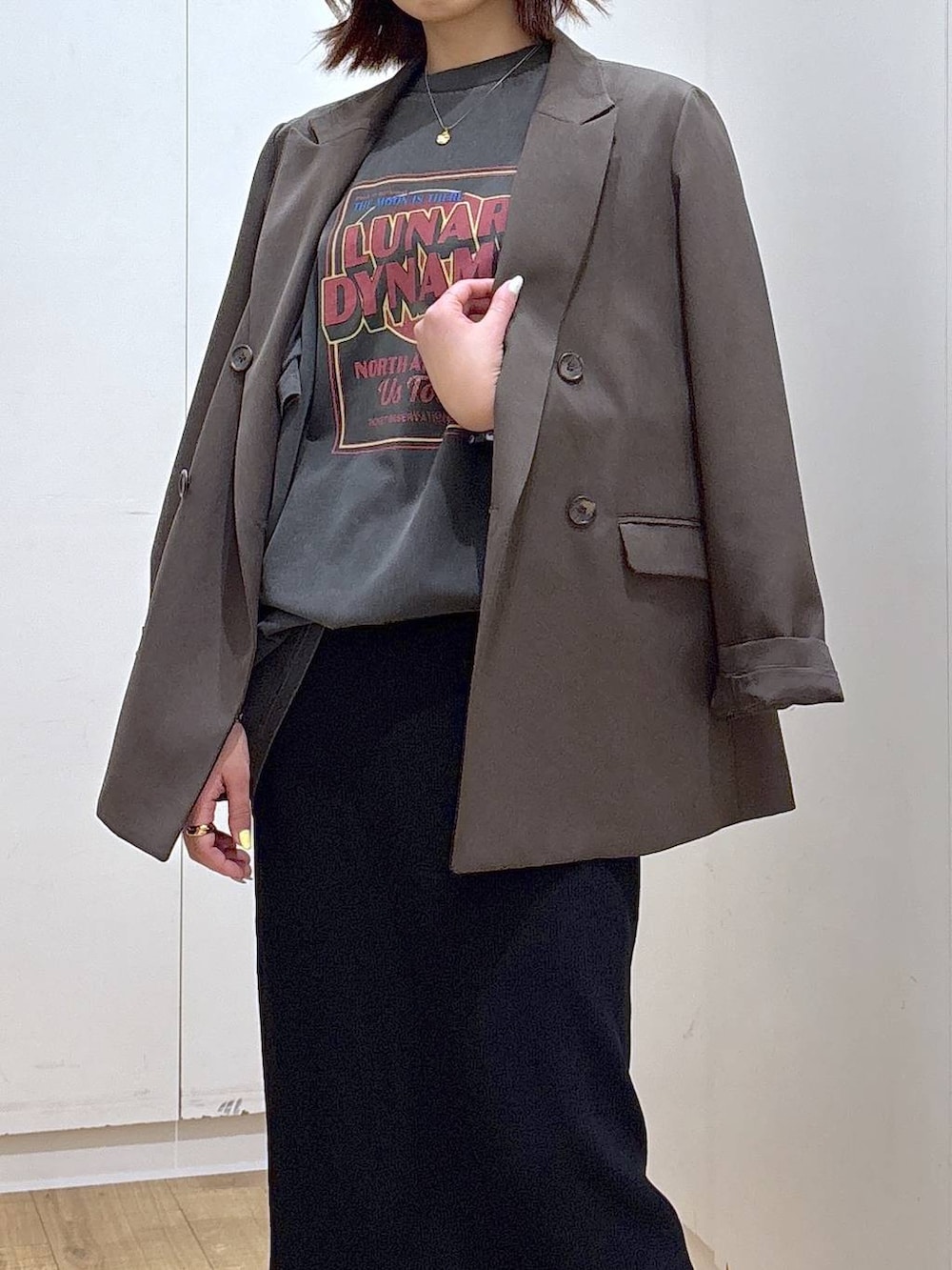 ブラウン系のテーラードジャケット、ブラック系のスカート、ゴールド系のネックレスを着用したレディースの春コーディネートの3枚目の写真