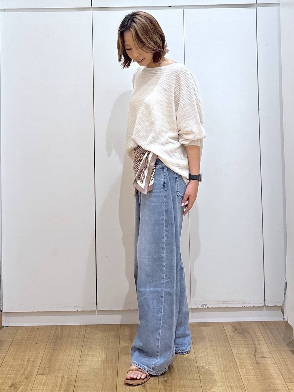 ホワイト系のキャミソール、ブルー系のデニムパンツ、ホワイト系のニット/セーターを着用したレディースの春コーディネートの4枚目の写真