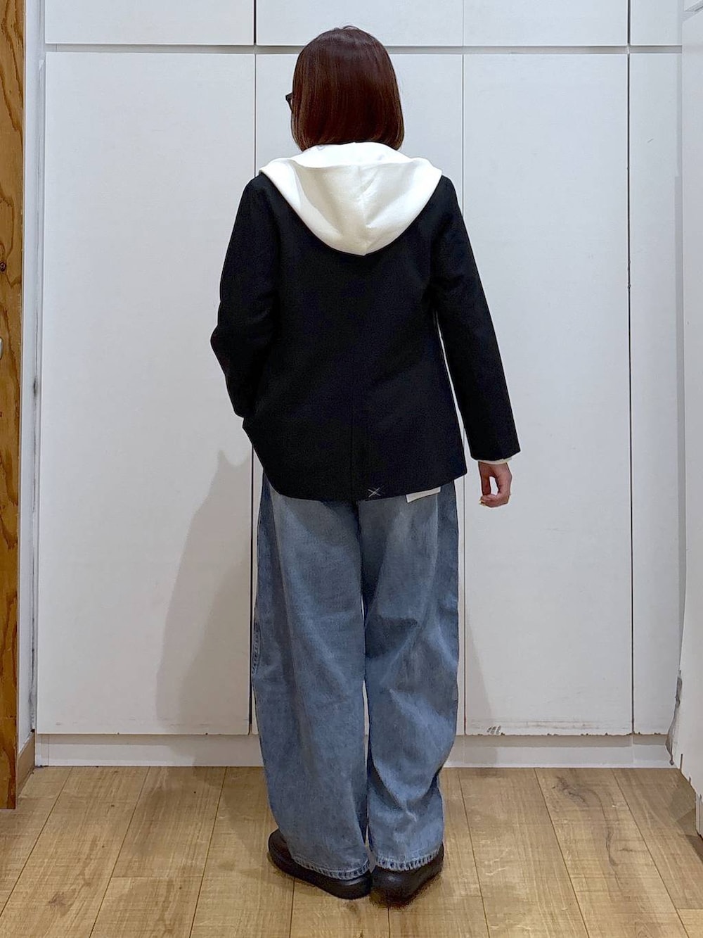 ホワイト系のパーカー、ブラック系のノーカラージャケット、ブルー系のデニムパンツを着用したレディースの春コーディネートの5枚目の写真