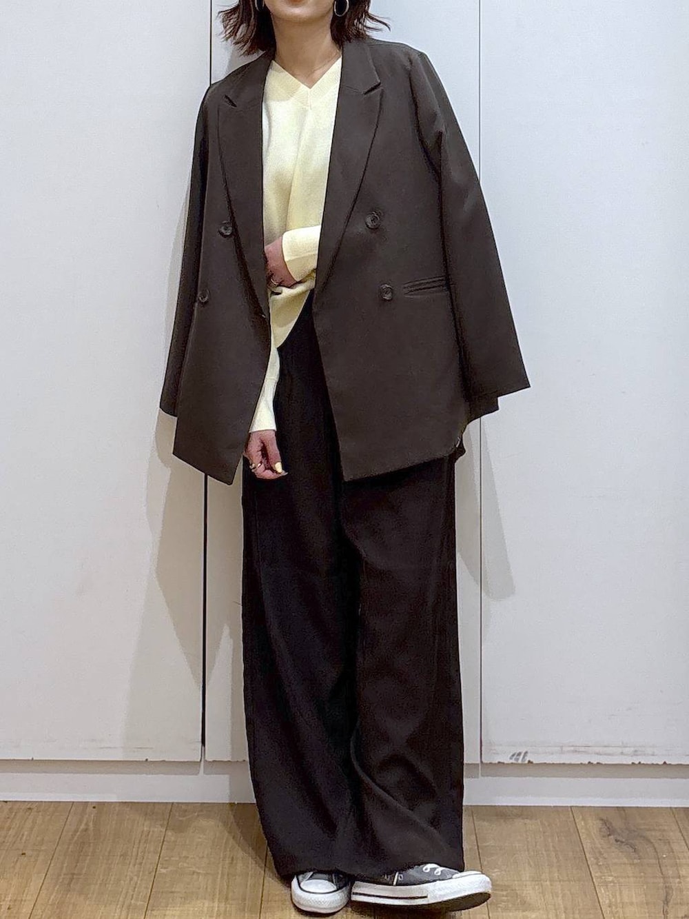 イエロー系のニット/セーター、ブラウン系のテーラードジャケット、ブラウン系のその他パンツを着用したレディースの春コーディネートの3枚目の写真