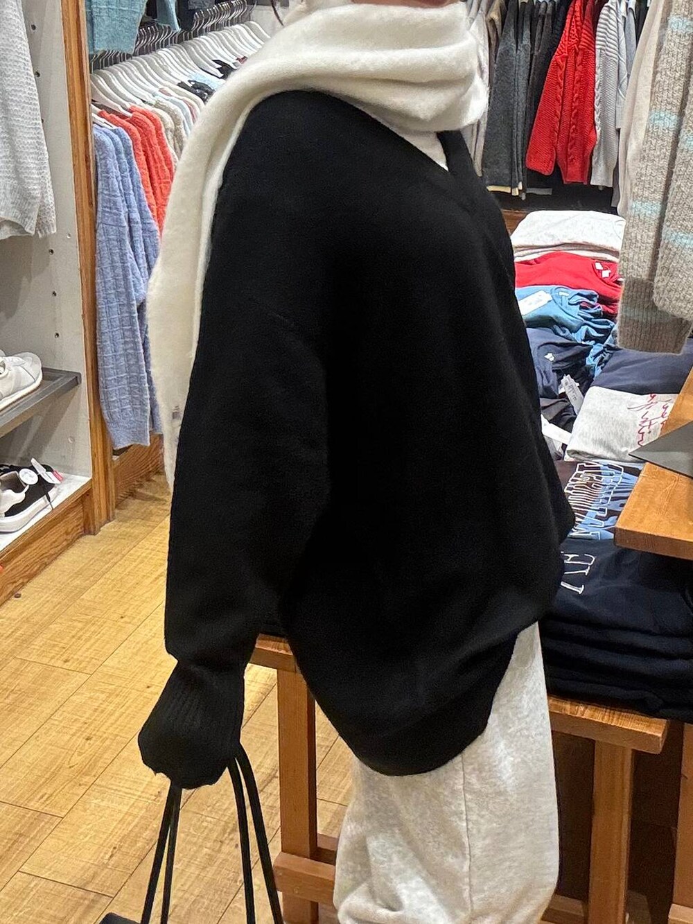 ブラック系のボストンバッグ、ブラック系のニット/セーター、ホワイト系のTシャツ/カットソーを着用したレディースの冬コーディネートの3枚目の写真