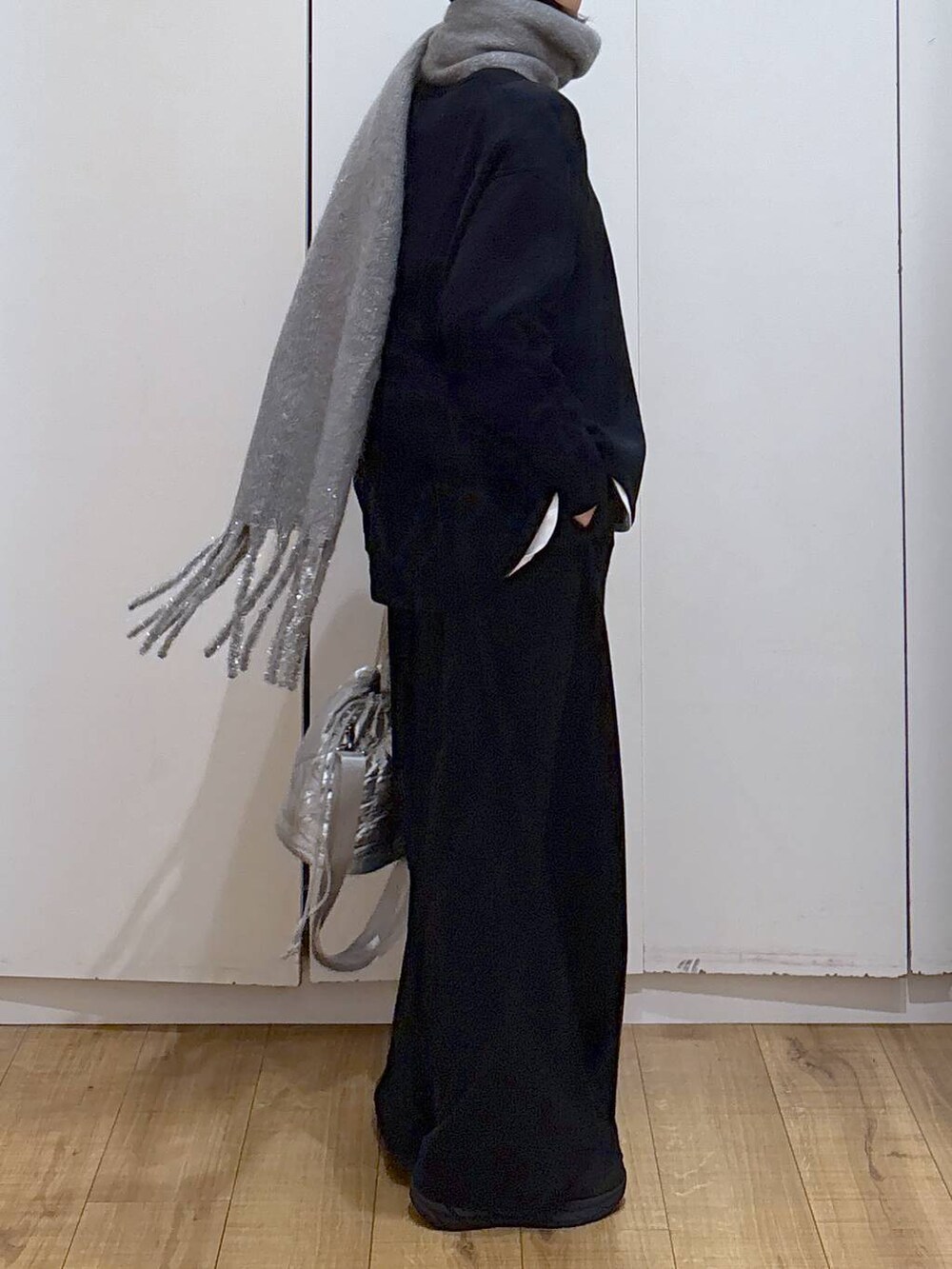 ブラック系のニット/セーター、シルバー系のハンドバッグ、ホワイト系のTシャツ/カットソーを着用したレディースの冬コーディネートの3枚目の写真