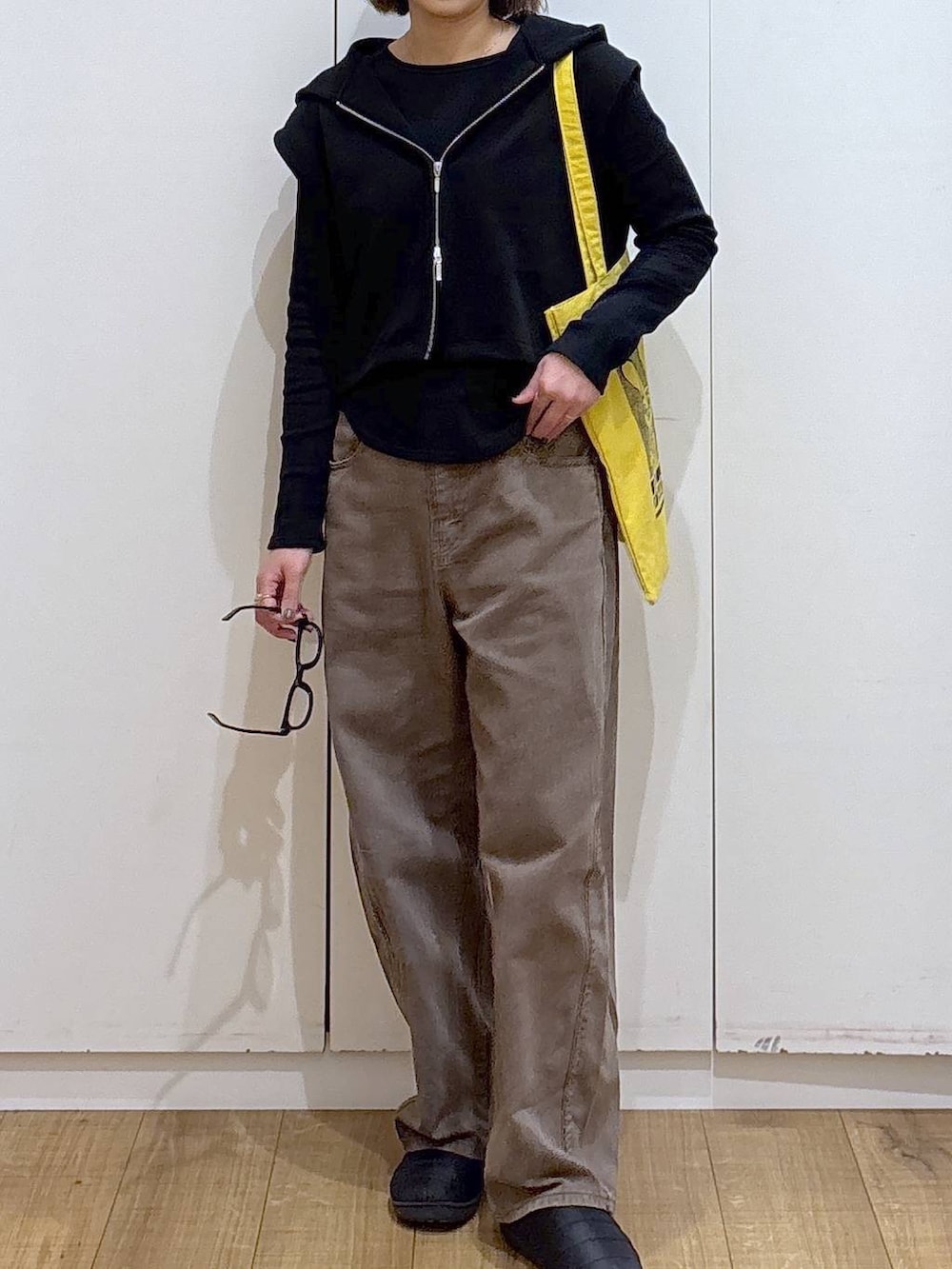 ブラウン系のデニムパンツ、イエロー系のトートバッグ、ブラック系のTシャツ/カットソーを着用したレディースの冬コーディネートの3枚目の写真