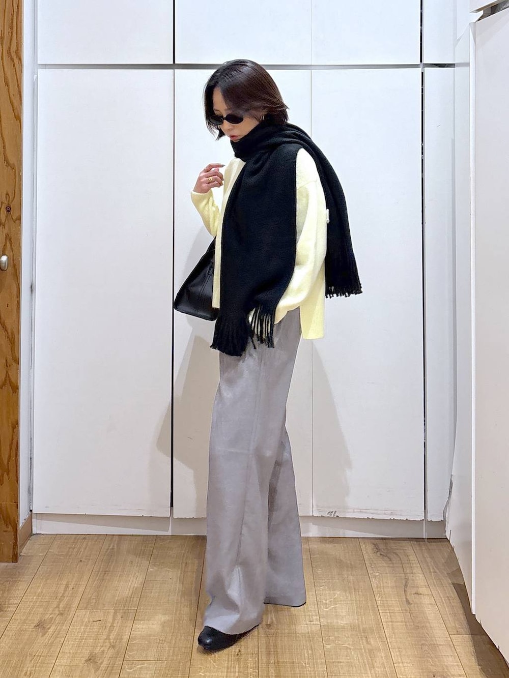 イエロー系のニット/セーター、グレー系のその他パンツ、ブラック系のショルダーバッグを着用したレディースの冬コーディネートの5枚目の写真
