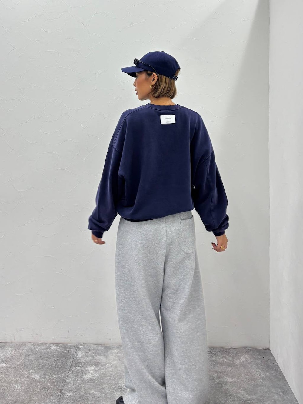 ブラック系のスニーカー、グレー系のその他パンツ、ブルー系のキャップを着用したレディースの秋コーディネートの4枚目の写真