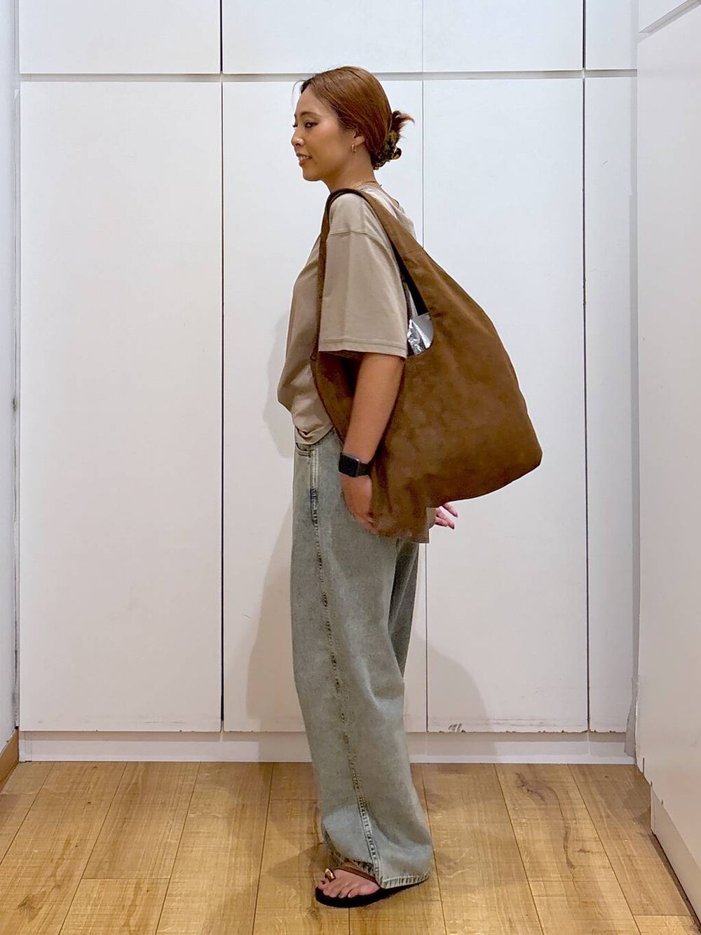 ブラウン系のサンダル、ベージュ系のTシャツ/カットソー、ブルー系のデニムパンツを着用したレディースの秋コーディネートの6枚目の写真