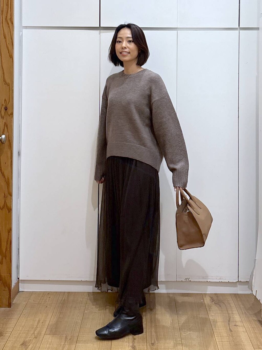 ベージュ系のショルダーバッグ、ブラウン系のワンピース、ブラック系のブーツを着用したレディースの秋コーディネートの2枚目の写真