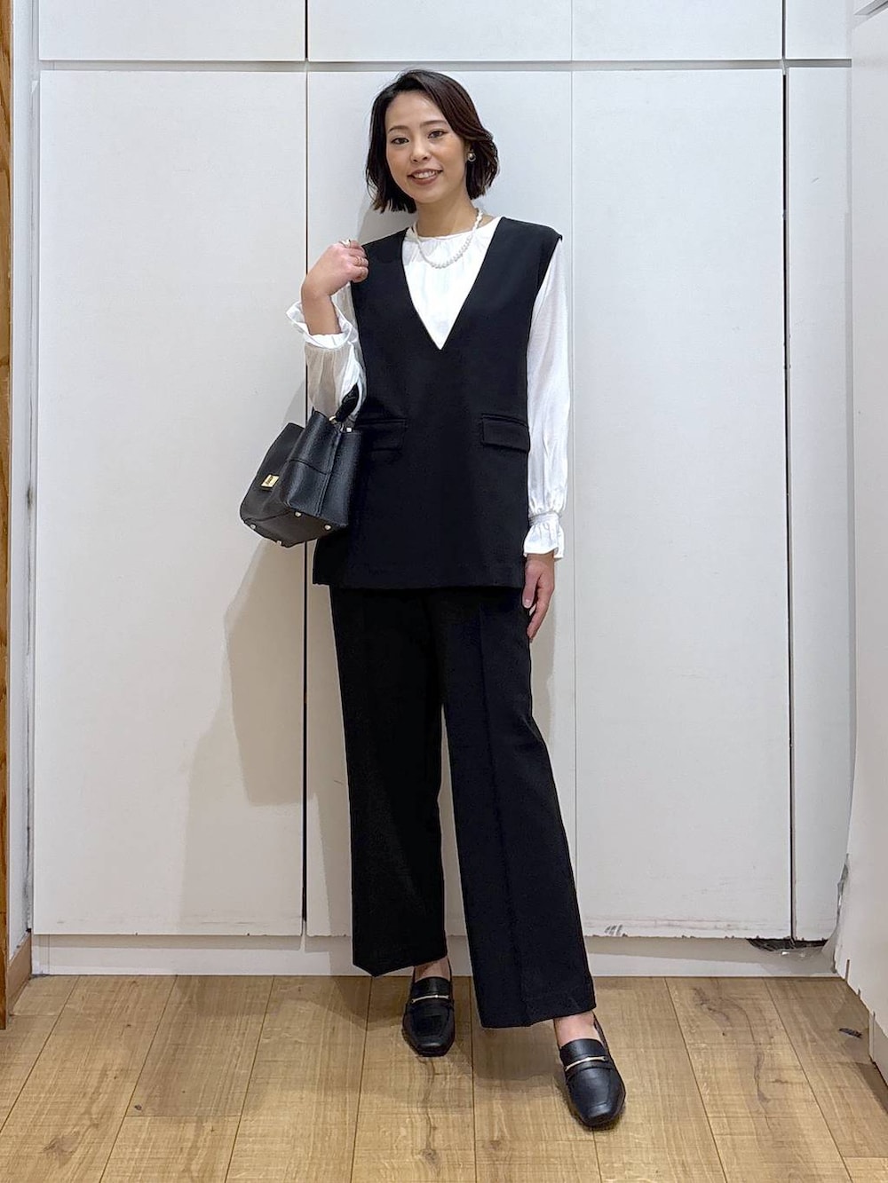 ブラック系のローファー、ブラック系のセットアップ、ブラック系のショルダーバッグを着用したレディースの冬コーディネートの3枚目の写真