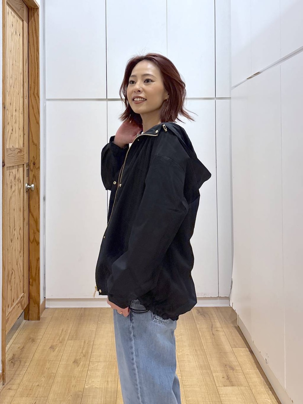 ブルー系のデニムパンツ、ブラック系のマウンテンパーカー、ブラウン系のカーディガン/ボレロを着用したレディースの春コーディネートの5枚目の写真