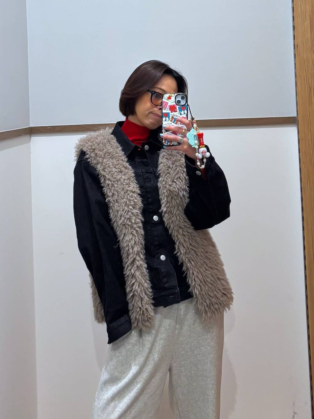 レッド系のニット/セーター、ブラック系のデニムジャケット、ゴールド系のピアス(両耳用)を着用したレディースの冬コーディネートの4枚目の写真