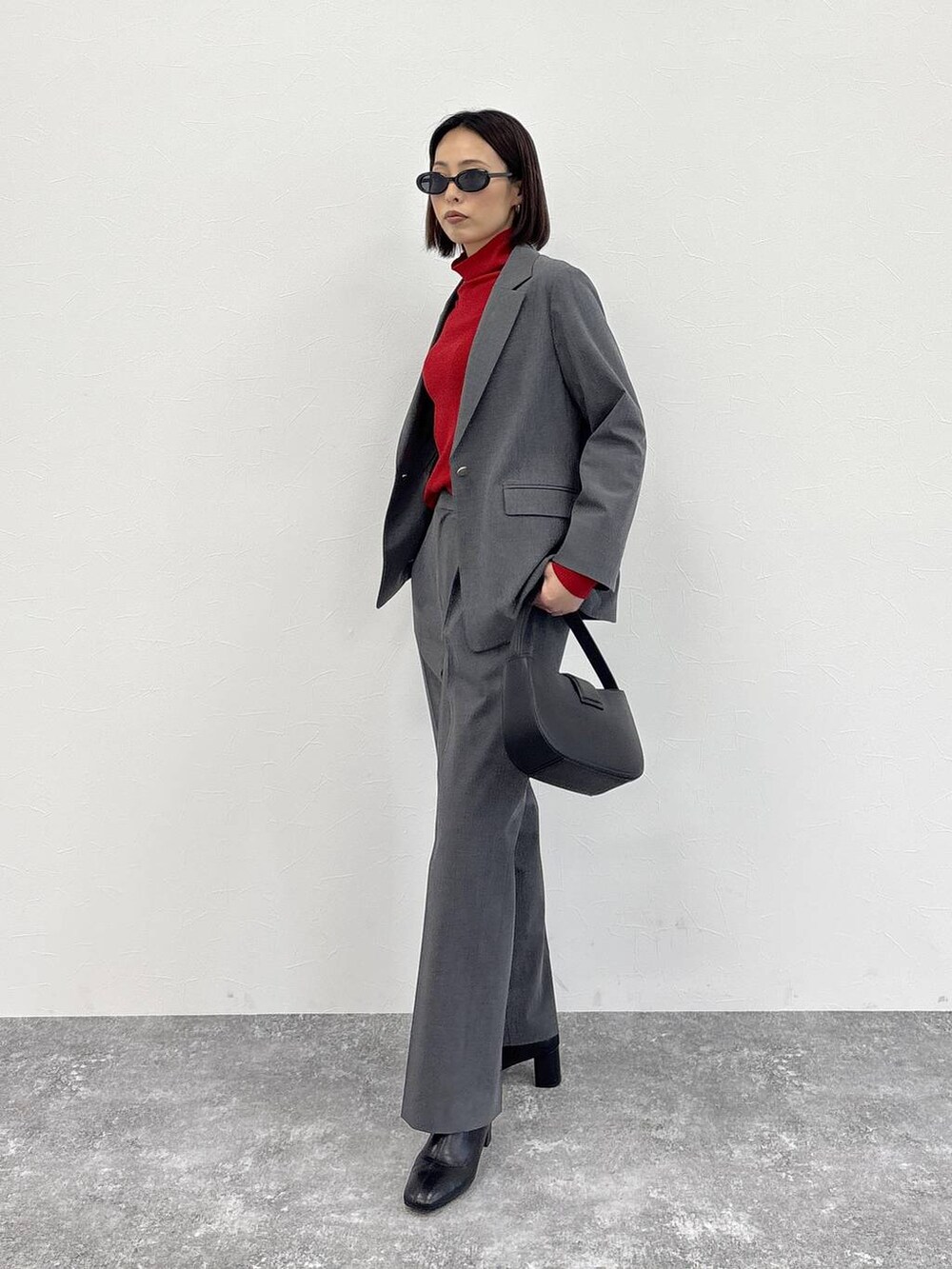 グレー系のスラックス、グレー系のテーラードジャケット、ブラック系のブーツを着用したレディースの冬コーディネートの2枚目の写真