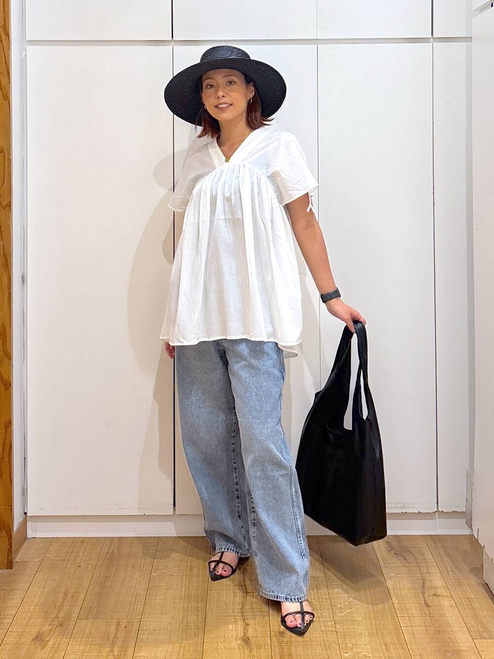 ブルー系のデニムパンツ、ブラック系のサンダル、ホワイト系のシャツ/ブラウスを着用したレディースの夏コーディネートの2枚目の写真