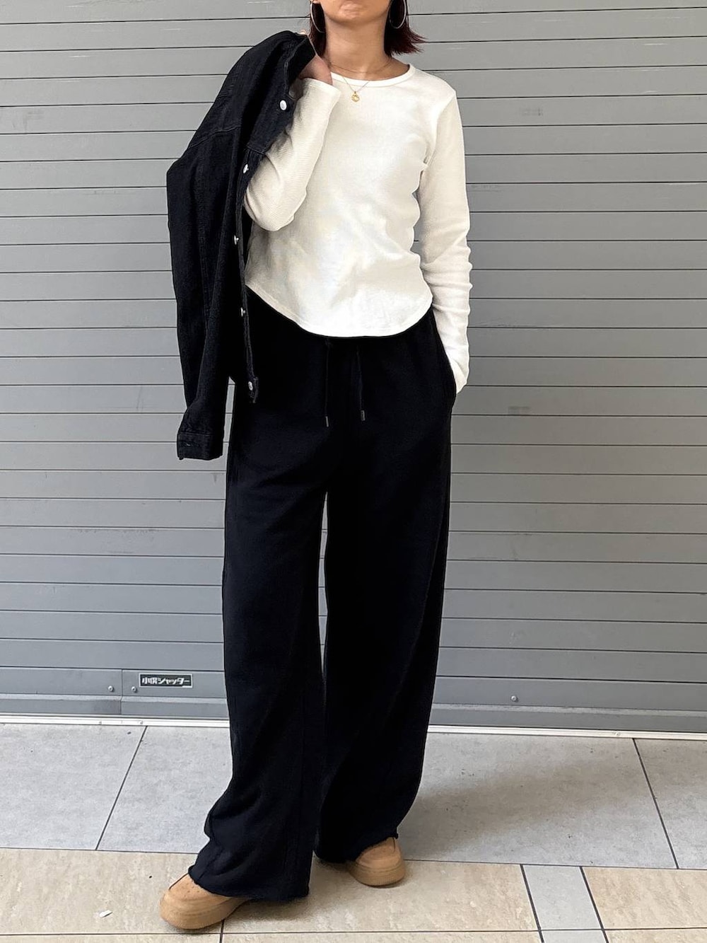 ブラック系のデニムジャケット、ブラック系のスウェットパンツ、ゴールド系のネックレスを着用したレディースの春コーディネートの6枚目の写真