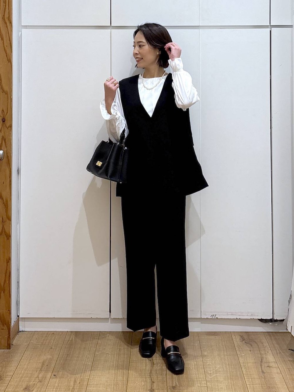 ブラック系のローファー、ブラック系のセットアップ、ブラック系のショルダーバッグを着用したレディースの冬コーディネートの4枚目の写真