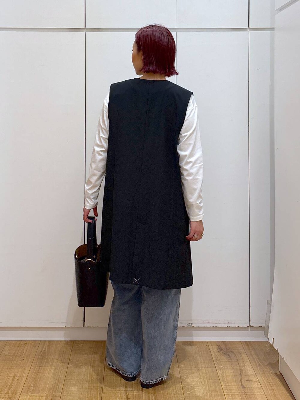 ブルー系のデニムパンツ、ブラック系のローファー、ブラック系のベストを着用したレディースの春コーディネートの4枚目の写真