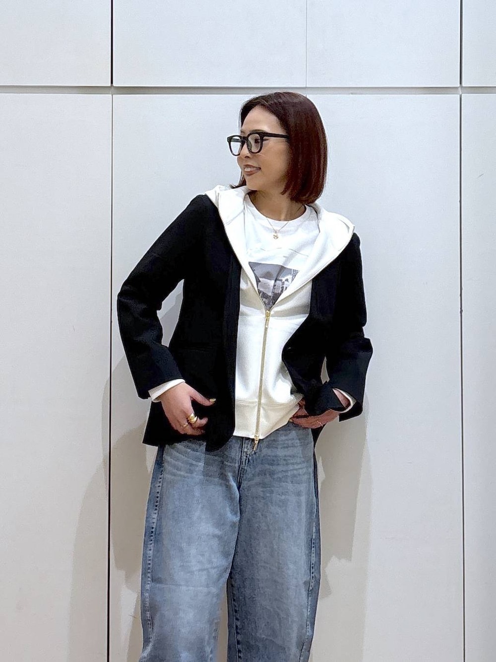 ホワイト系のパーカー、ブラック系のノーカラージャケット、ブルー系のデニムパンツを着用したレディースの春コーディネートの2枚目の写真