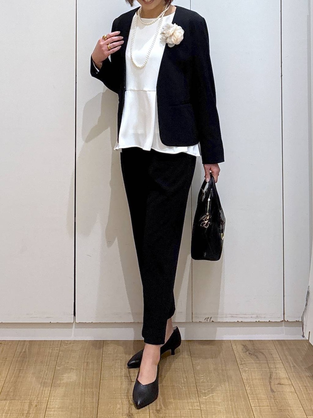 ブラック系のショルダーバッグ、ブラック系のパンプス、ブラック系のセットアップを着用したレディースの冬コーディネートの5枚目の写真