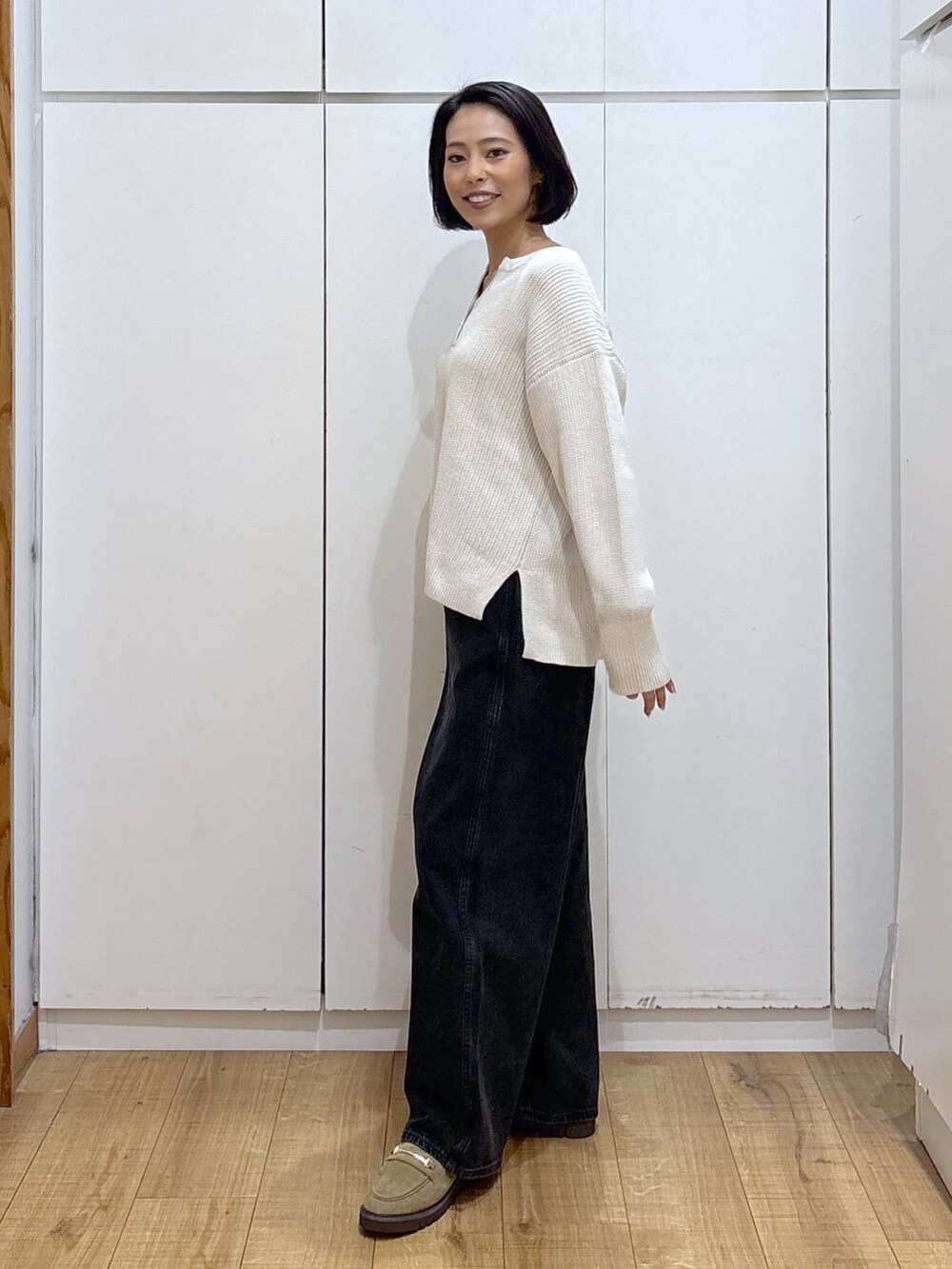 ブラック系のデニムパンツ、ベージュ系のローファー、ベージュ系のニット/セーターを着用したレディースの秋コーディネートの5枚目の写真