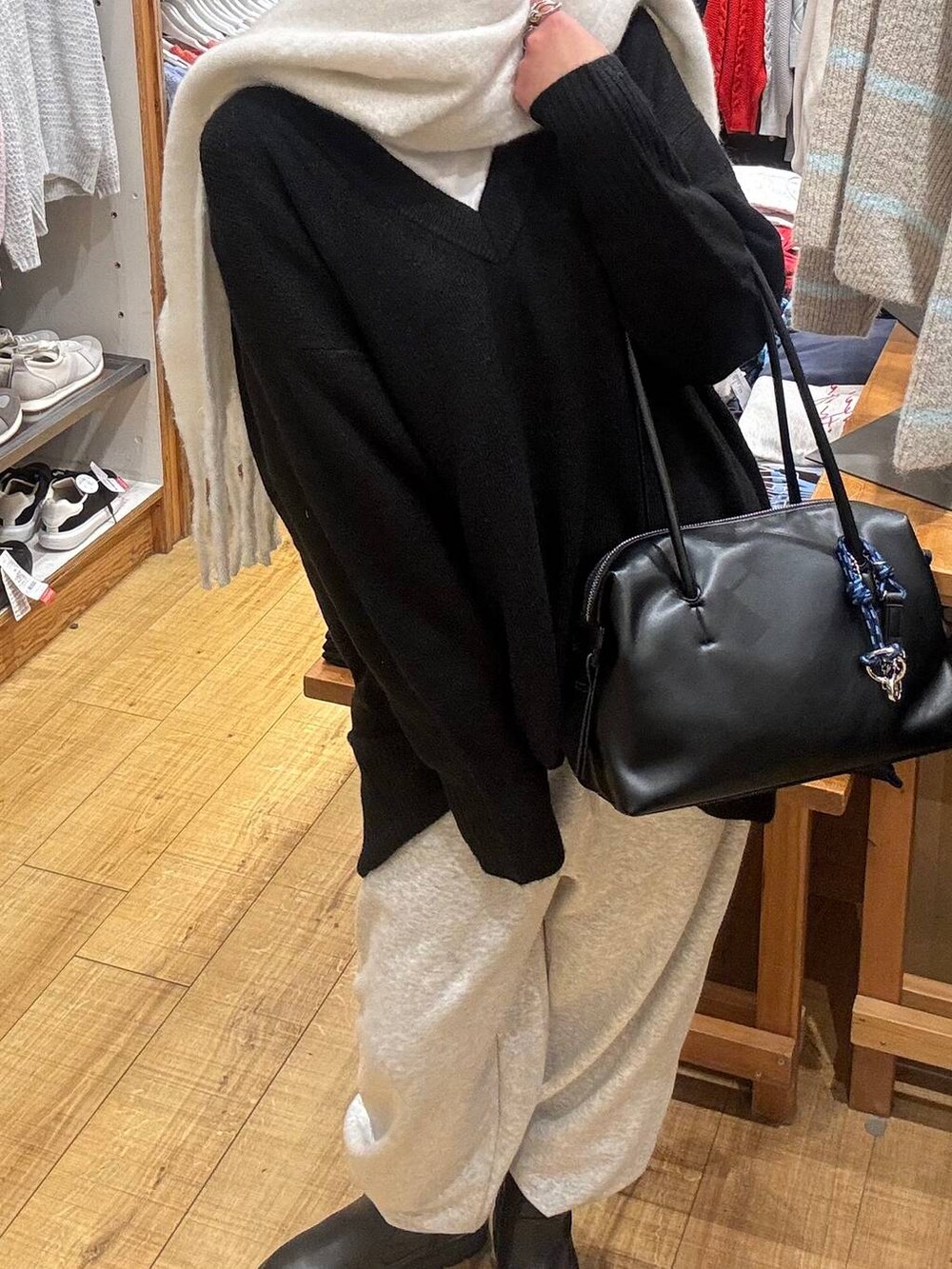 ブラック系のボストンバッグ、ブラック系のニット/セーター、ホワイト系のTシャツ/カットソーを着用したレディースの冬コーディネートの2枚目の写真