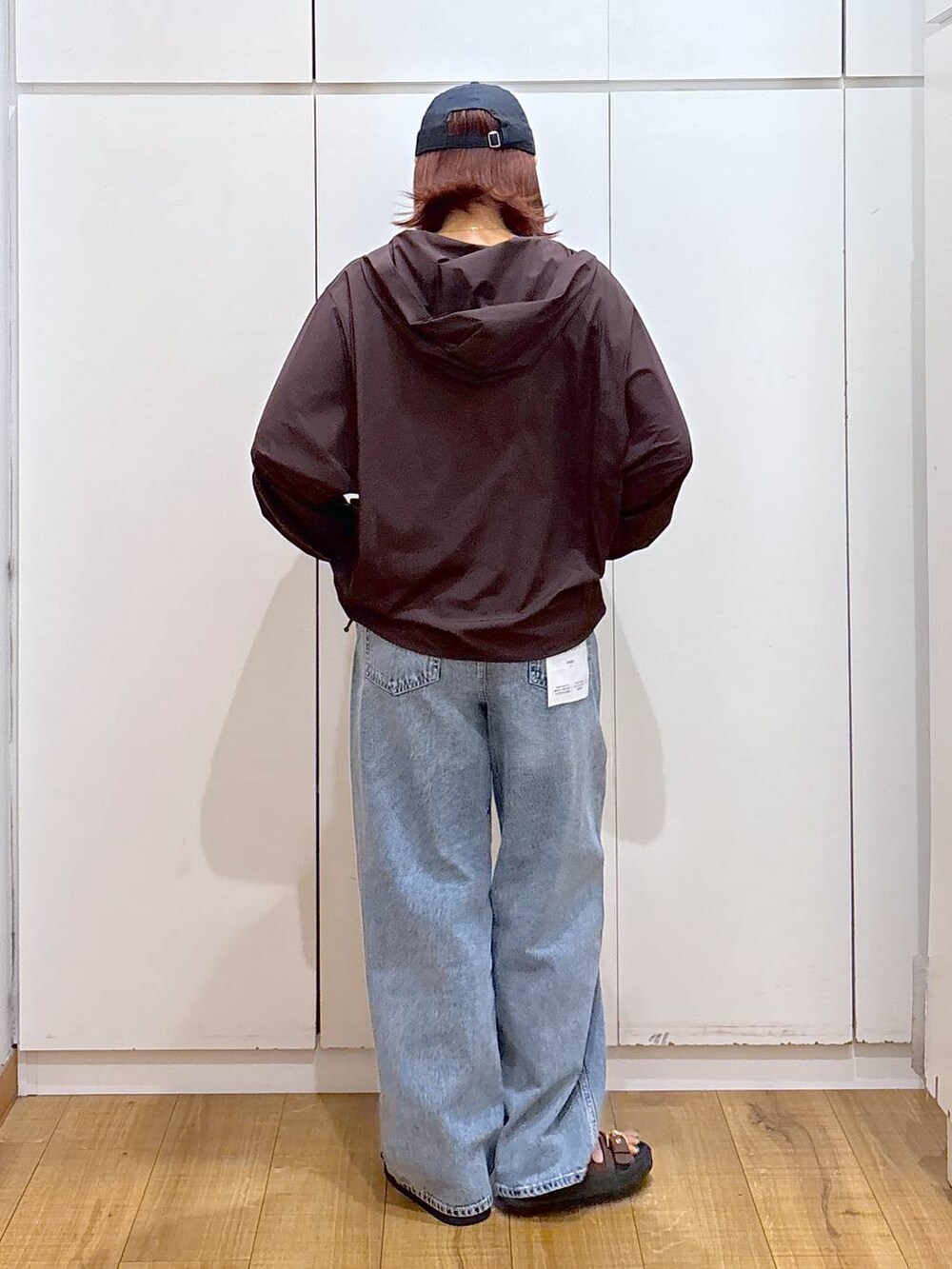 ブルー系のデニムパンツ、ブラウン系のマウンテンパーカー、ブルー系のキャップを着用したレディースの夏コーディネートの3枚目の写真