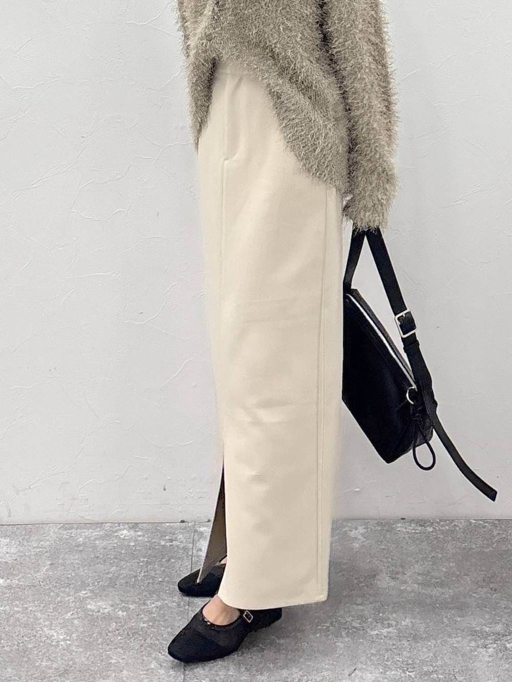 ブラック系のショルダーバッグ、ベージュ系のスカート、ゴールド系のピアス(両耳用)を着用したレディースの冬コーディネートの6枚目の写真