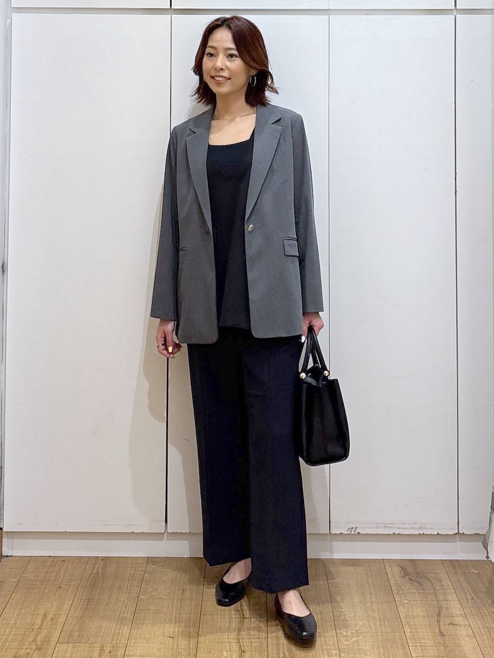 ブラック系のパンプス、ブラック系のセットアップ、ブラック系のトートバッグを着用したレディースの春コーディネートの2枚目の写真