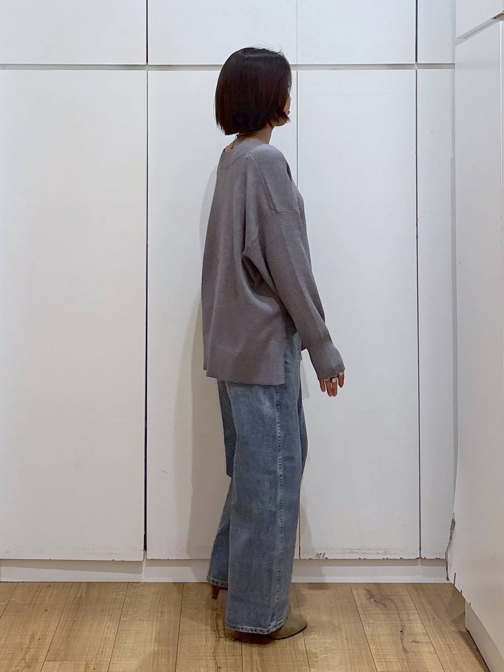 グレー系のニット/セーター、ベージュ系のブーツ、ブルー系のデニムパンツを着用したレディースの冬コーディネートの4枚目の写真