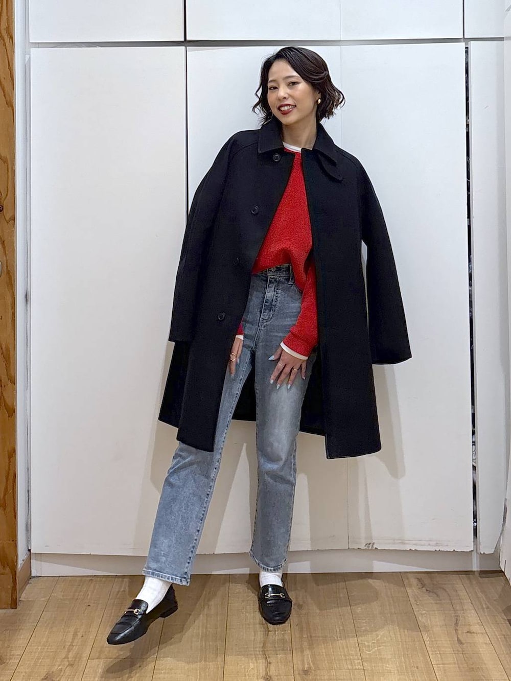 ブラック系のローファー、ブラック系のステンカラーコート、ブルー系のデニムパンツを着用したレディースの冬コーディネートの2枚目の写真