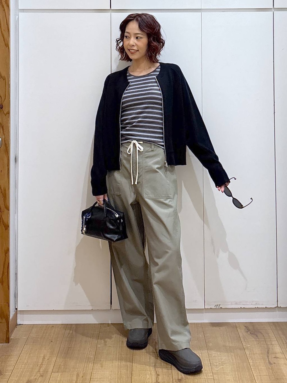 グリーン系のその他パンツ、ブラック系のカーディガン/ボレロ、ブラック系のボストンバッグを着用したレディースの春コーディネートの2枚目の写真