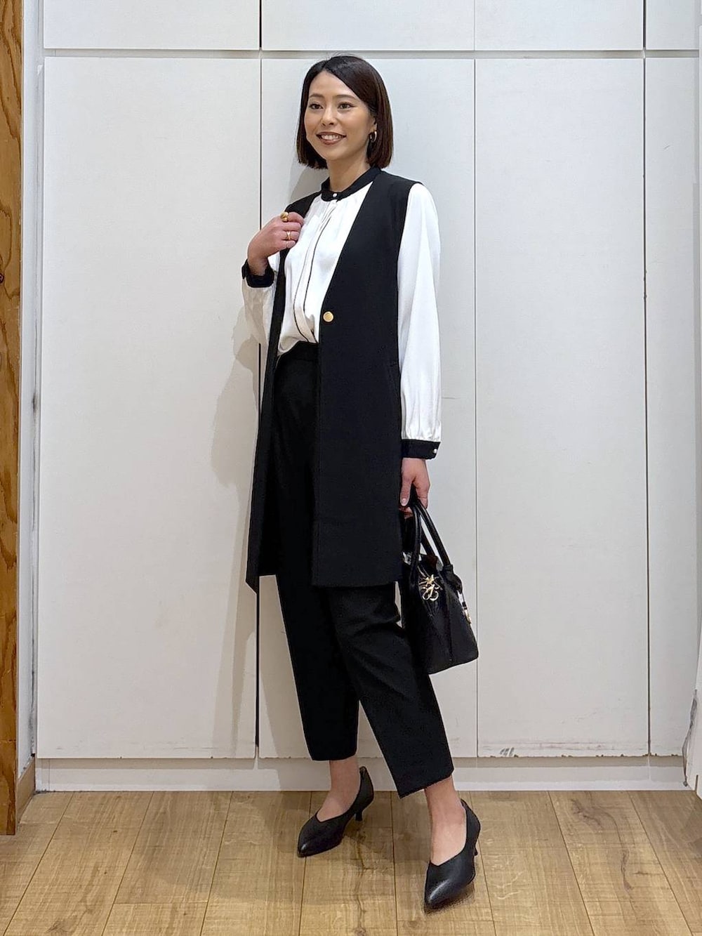 ブラック系のショルダーバッグ、ブラック系のパンプス、ブラック系のスラックスを着用したレディースの冬コーディネートの3枚目の写真