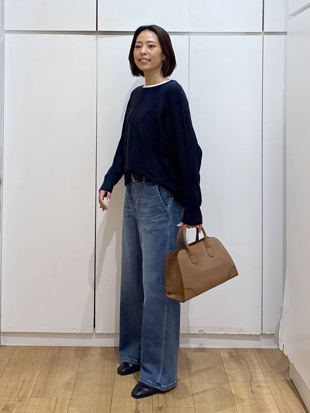 ベージュ系のショルダーバッグ、ブルー系のニット/セーター、ブラック系のブーツを着用したレディースの秋コーディネートの3枚目の写真