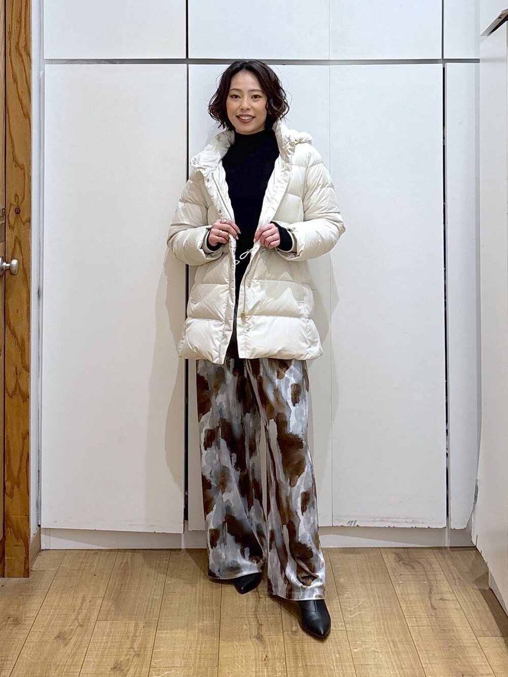 ベージュ系のダウンジャケット/コート、ブラック系のニット/セーター、ブラック系のブーツを着用したレディースの冬コーディネートの3枚目の写真