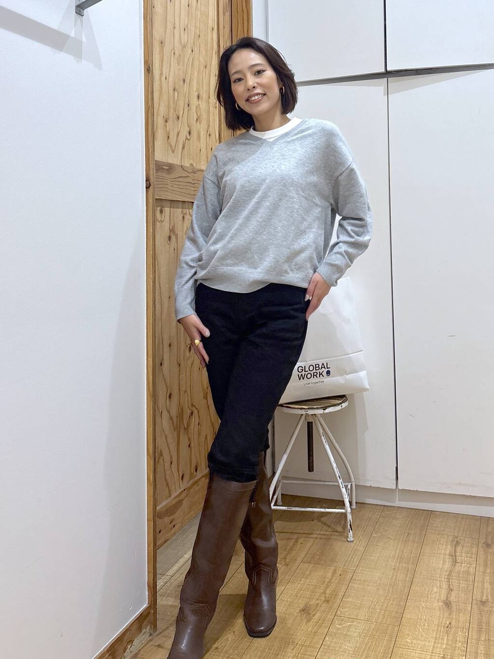 ブラック系のデニムパンツ、ブラウン系のブーツ、グレー系のニット/セーターを着用したレディースの秋コーディネートの4枚目の写真