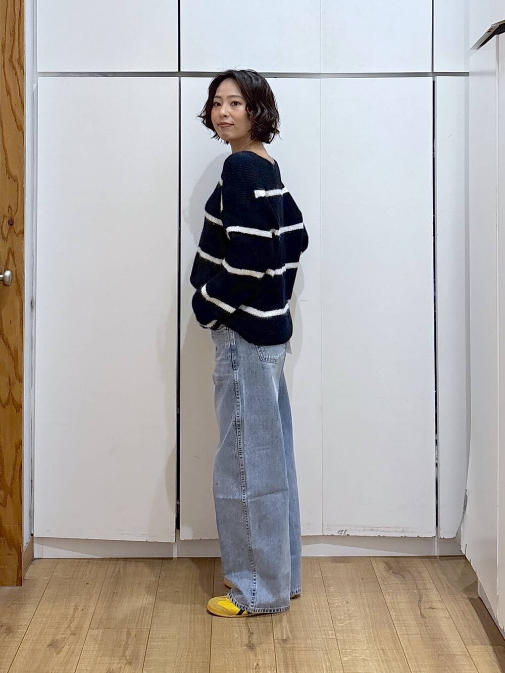 ブルー系のデニムパンツ、ブルー系のニット/セーター、ゴールド系のピアス(両耳用)を着用したレディースの冬コーディネートの5枚目の写真