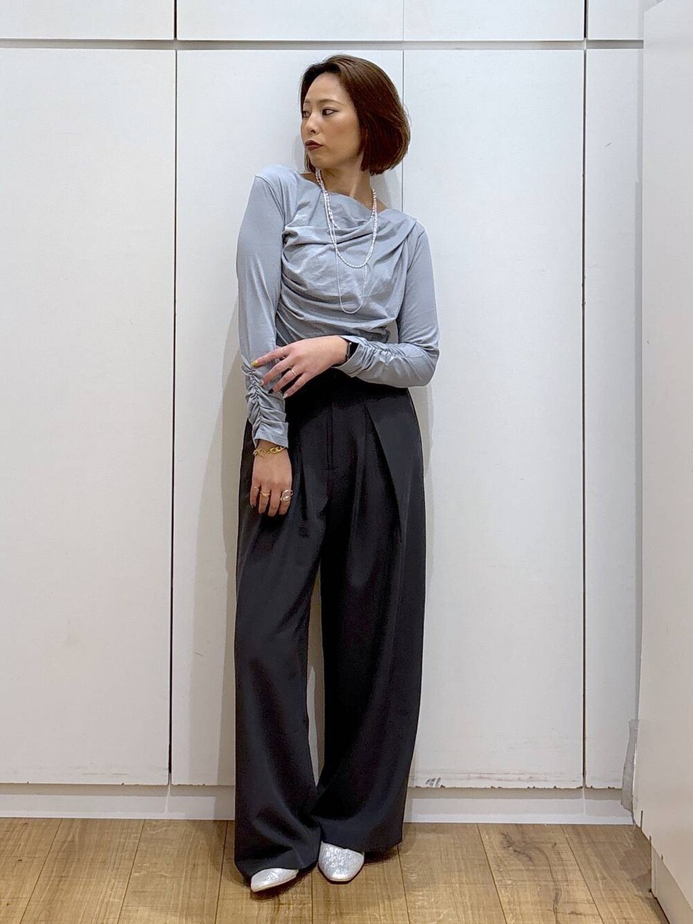 シルバー系のパンプス、グレー系のTシャツ/カットソー、グレー系のスラックスを着用したレディースの秋コーディネートの2枚目の写真