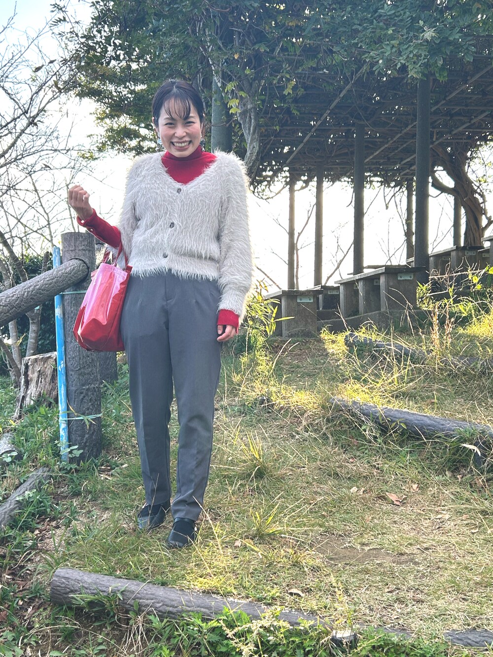 グレー系のカーディガン/ボレロ、グレー系のその他パンツ、レッド系のトートバッグを着用したレディースの秋コーディネートの2枚目の写真