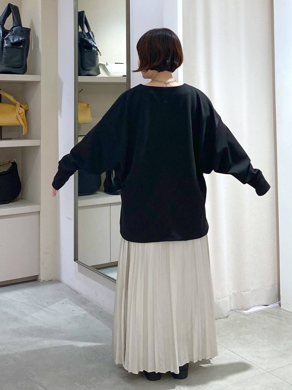 ベージュ系のトートバッグ、ブラック系のTシャツ/カットソー、ベージュ系のスカートを着用したレディースの秋コーディネートの4枚目の写真