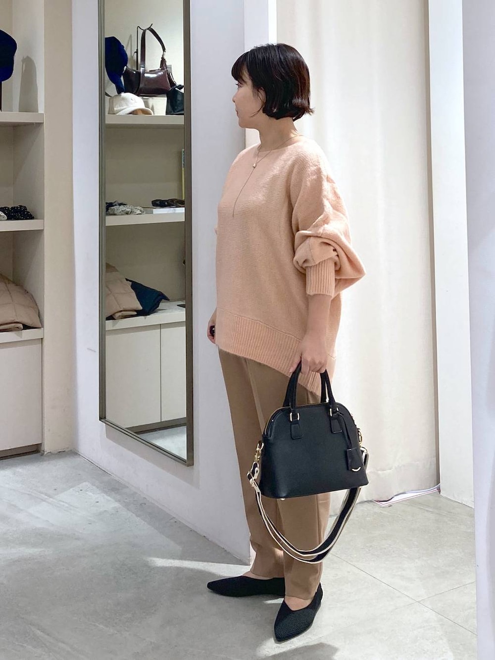 ブラック系のハンドバッグ、ピンク系のニット/セーター、ベージュ系のスラックスを着用したレディースの秋コーディネートの4枚目の写真